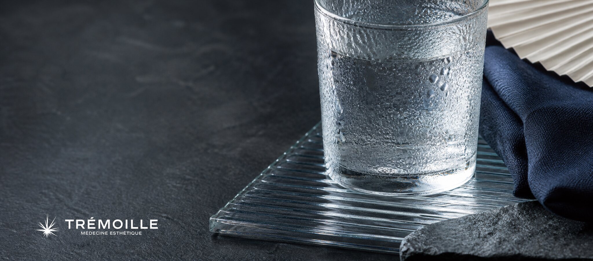 Verre couvert de condensation et linge bleu illustrant la transpiration excessive en été