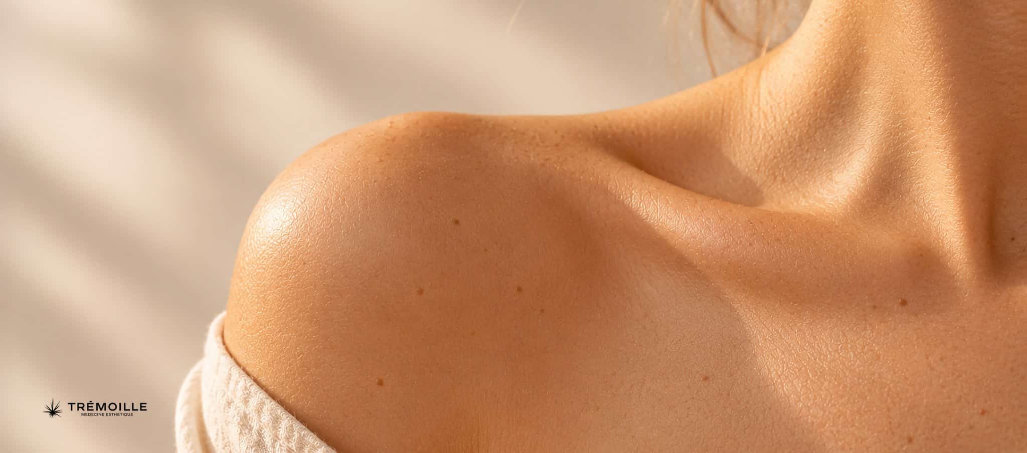 Épaule et clavicule d’une personne en lumière douce, peau nette et texture naturelle