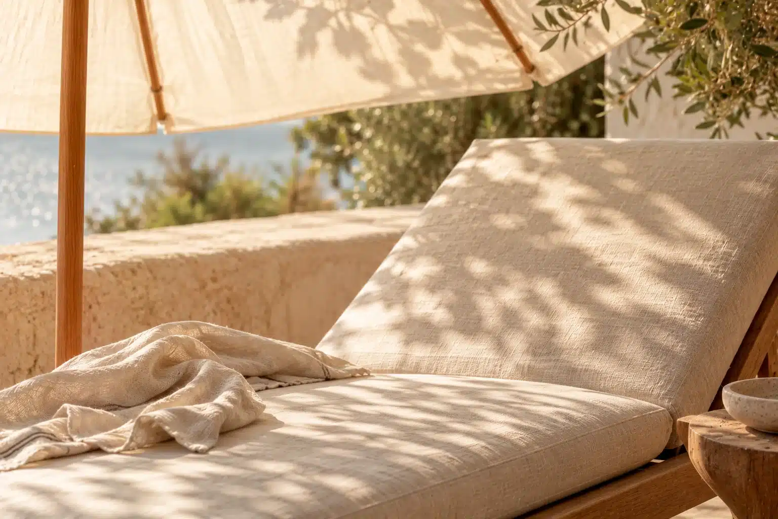 Ombre d’un parasol en toile crème sur une chaise longue en lin