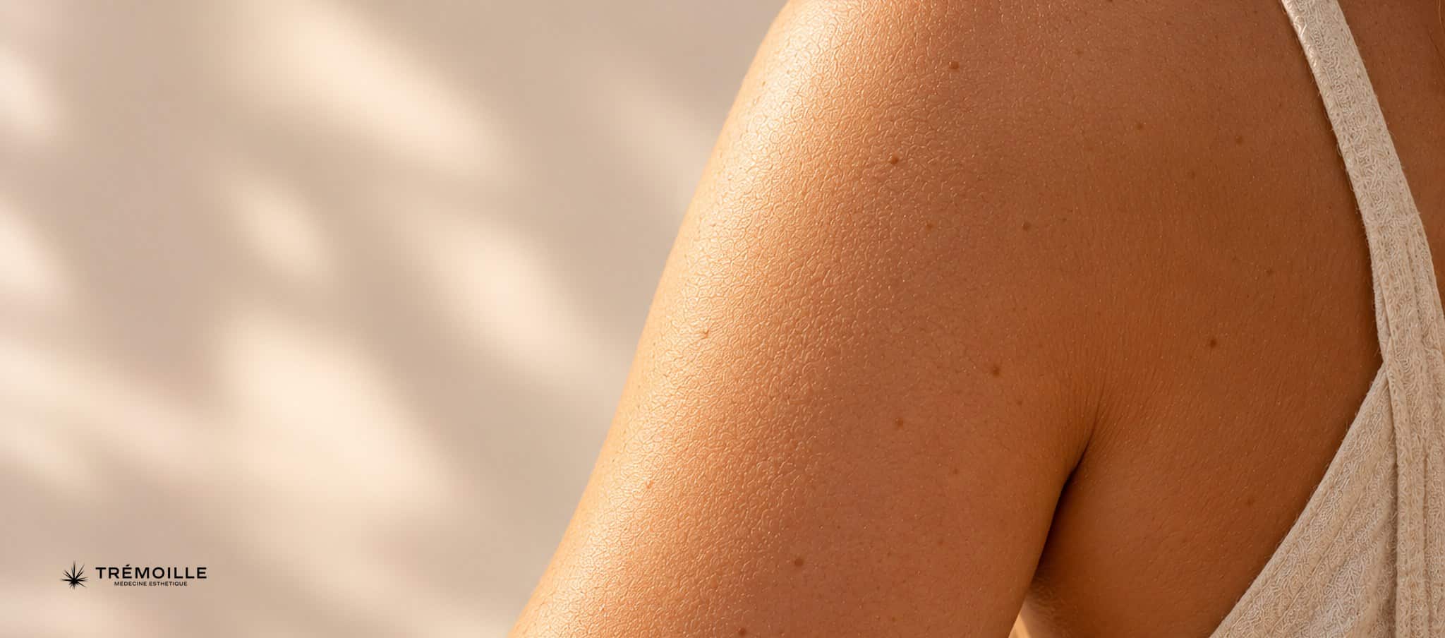 Arrière du bras et épaule d’une personne en lumière rasante douce, texture de peau visible